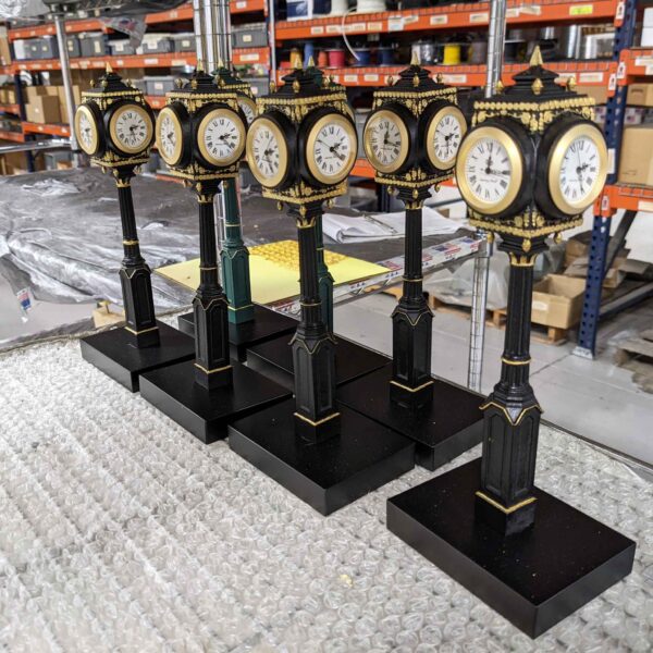 A group of small miniature post clocks in various stages of production in a factory setting."