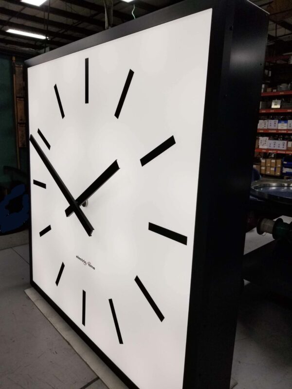 A large square tower clock with a 72 inch diameter being manufactured in a factory