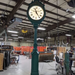 Almy’s Street Clock in Electric Time Company’s factory during testing, with illuminated dial displaying 'Essex County’s Shopping Centre.